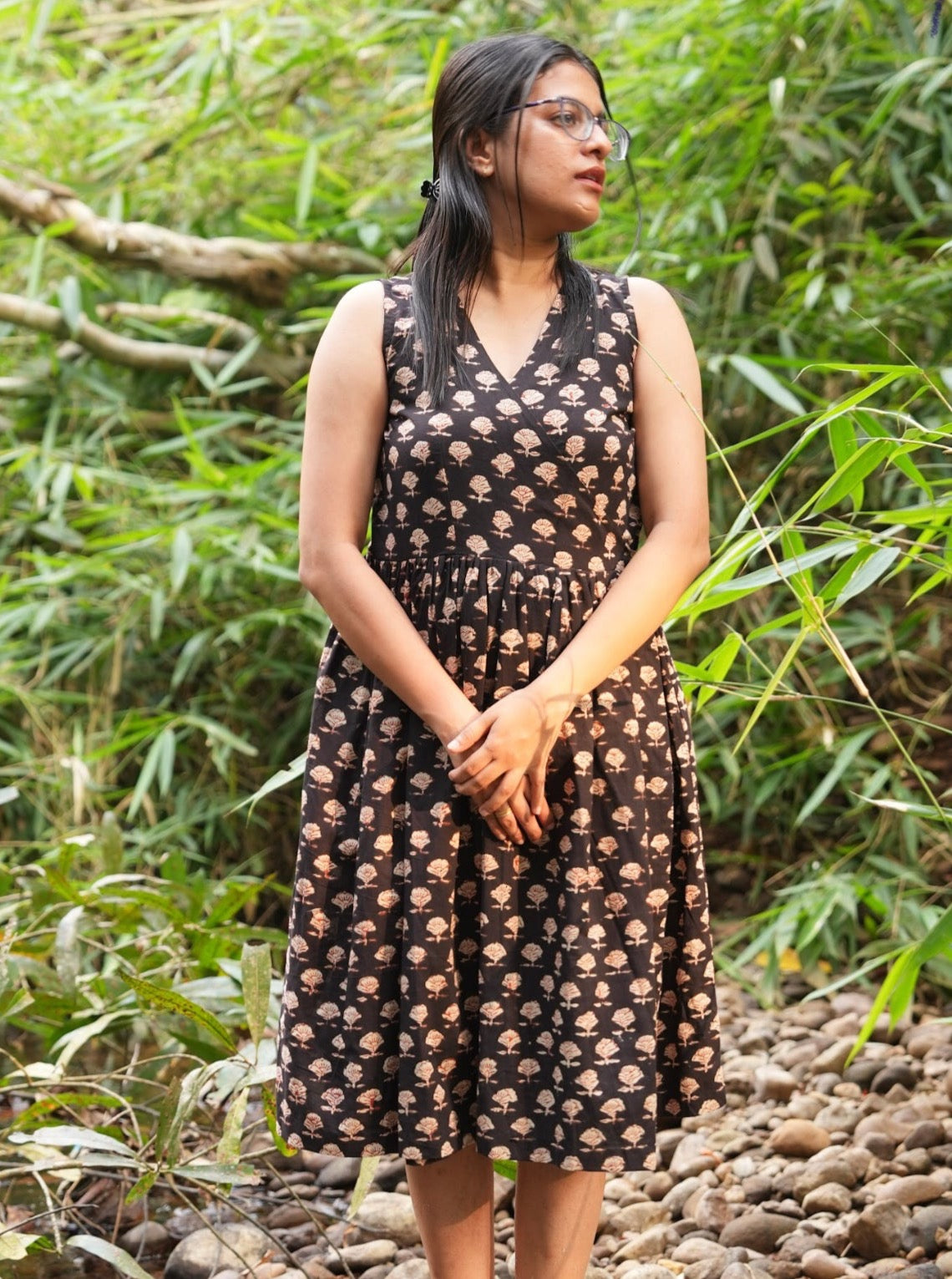 Black hand block printed cotton wrap dress. Sleeveless midi style offers cool comfort for vacations & casual wear. Shop this versatile dress now.